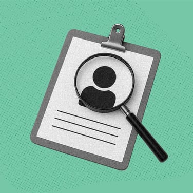 A magnifying glass hovers over a resume with a person icon on it to imply examining someone closely.