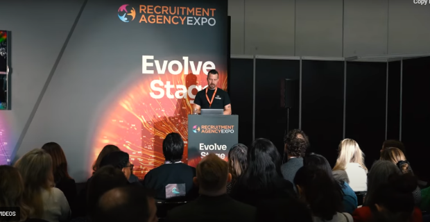 A speaker presenting at the Recruitment Agency Expo to an attentive audience.