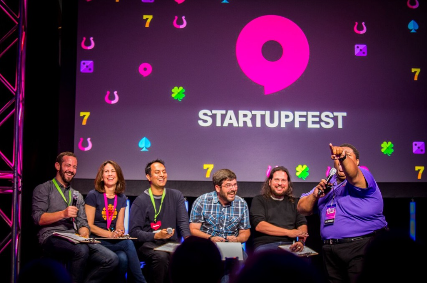 Speakers engaging and laughing on stage at the Startupfest conference for founders