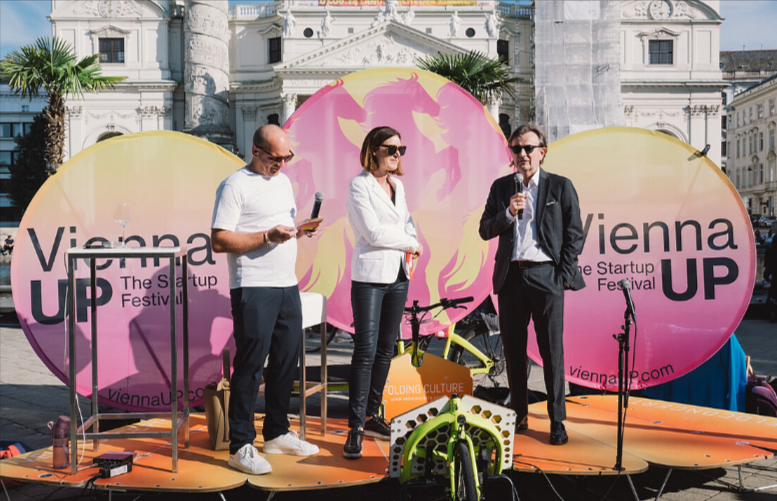 Three speakers engaging on stage at the ViennaUP conference for founders