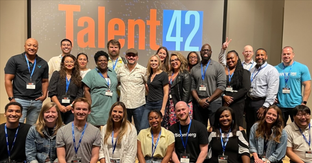 Talent42 attendees pose together for a group photo in front of the backdrop