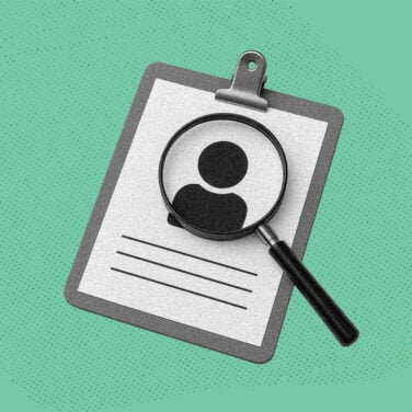 A magnifying glass hovers over a resume with a person icon on it to imply examining someone closely.