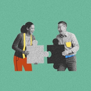 Two people put puzzle pieces together with smiles on their face to represent engaged employees working together